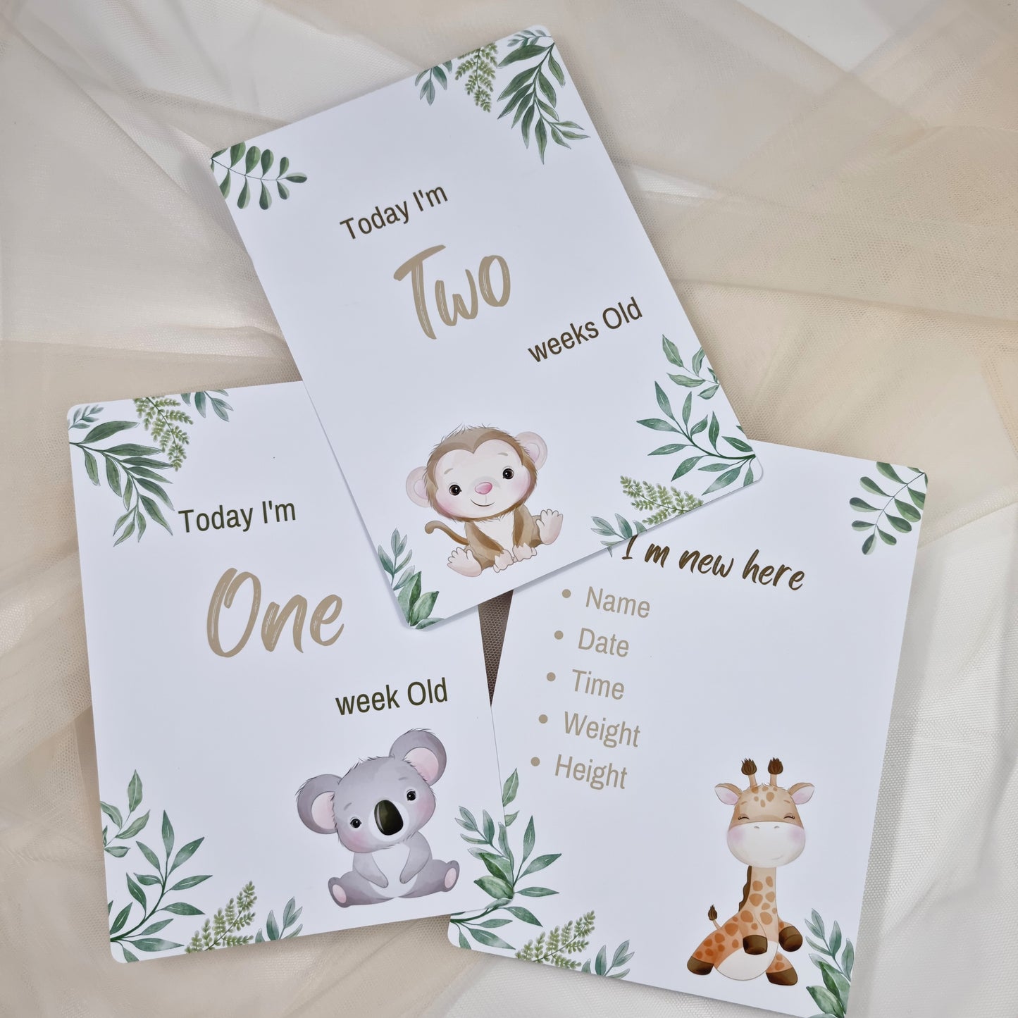 Three baby milestone cards with animal illustrations and text on a light background