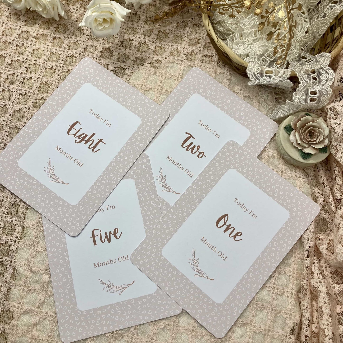 Four milestone cards for a baby's first year on a textured surface with decorative elements.