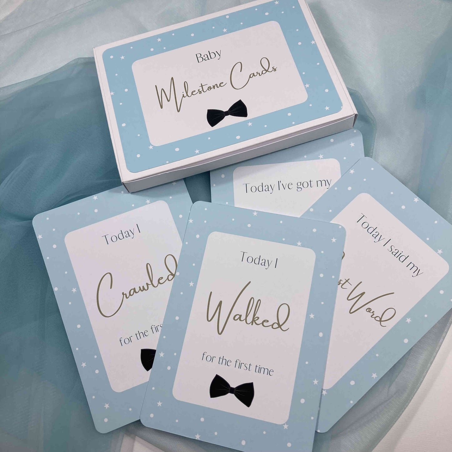 Baby milestone cards with blue and white design on a light blue fabric background