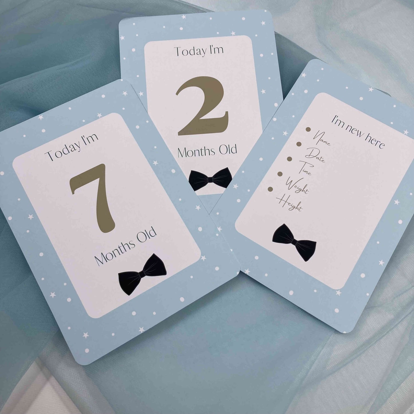 Three milestone cards for a baby's first year on a light blue background.