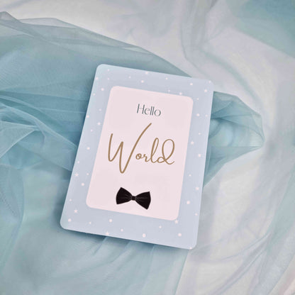 Card with 'Hello World' and a bow tie on a light blue fabric background