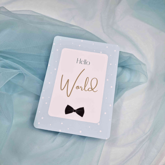 Card with 'Hello World' and a bow tie on a light blue fabric background